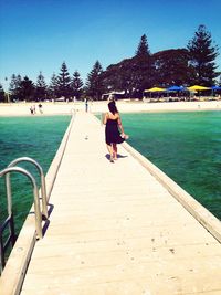 Rear view of woman standing on pier