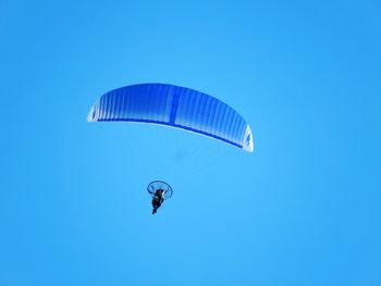 Low angle view of person paragliding against clear blue sky