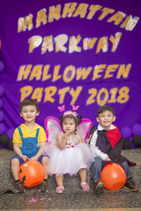 Cute children sitting against curtain during halloween party