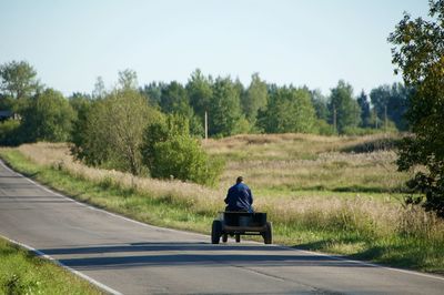 Rear view of man sitting on road against sky