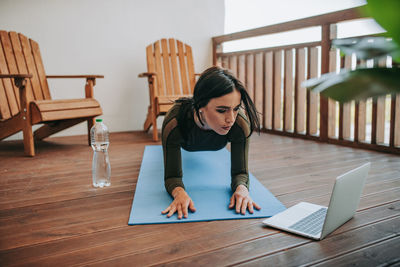 Young woman using phone while sitting on table