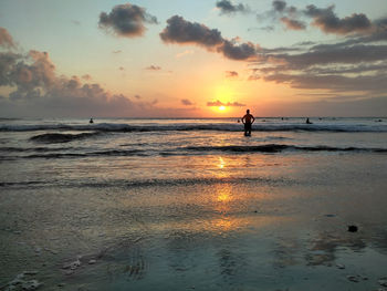 Silhouette person on beach against sky during sunset