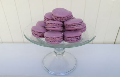 Pink macaroons stacked on cake stand on table against wood paneling