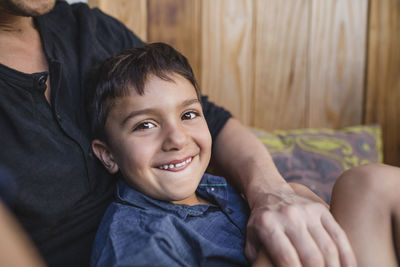 Portrait of smiling boy sitting with father