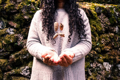 Midsection of woman throwing pine cones