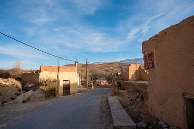 Road amidst abandoned buildings against sky