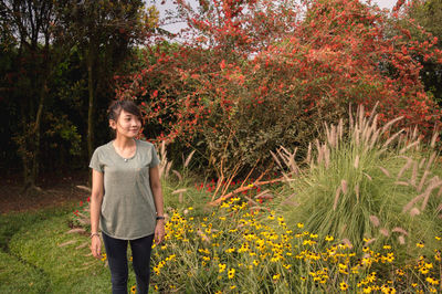 Portrait of smiling woman standing by plants