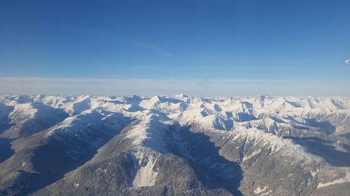 Scenic view of snowcapped mountains against blue sky