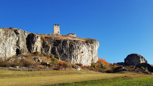 Low angle view of rocks against clear blue sky