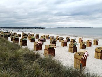 Hooded chairs on beach against sky