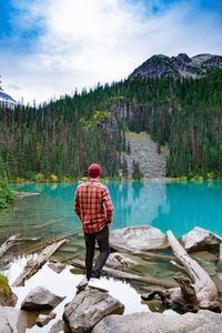 Rear view of man standing by lake against sky