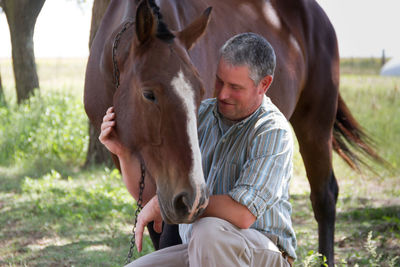 Man standing with horse against trees