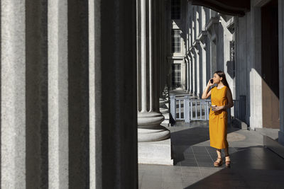 Woman talking on smart phone while standing near column at national gallery, singapore