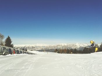 Snow covered landscape against clear blue sky