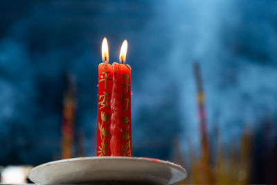 Low angle view of lit candles in plate against cloudy sky at dusk