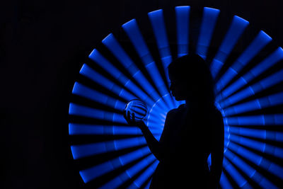 Silhouette girl standing against illuminated lighting equipment