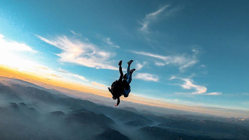 Man jumping in mid-air against sky during sunset