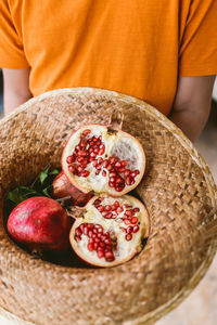 Midsection of person holding pomegranates in hat