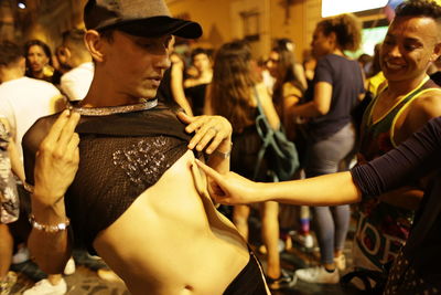 Woman touching man nipple on city street at night
