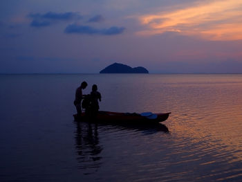 Silhouette of couple standing in sea near boat