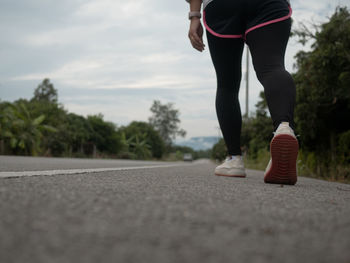 Low section of man skateboarding on road