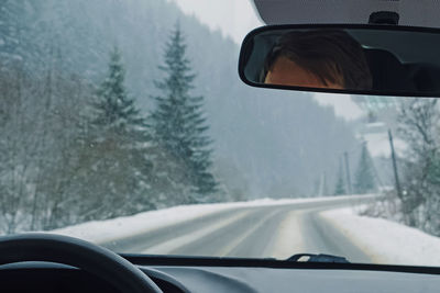 Driving through the winter snowy forest, view from the drivers side