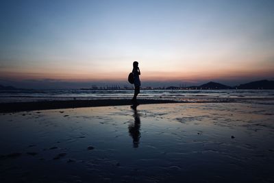 Silhouette man standing on beach against sky during sunset