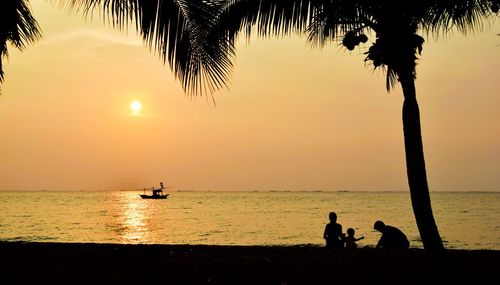 Silhouette people on beach against sky during sunset