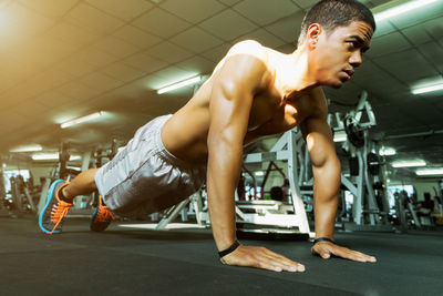 Full length of shirtless man exercising at gym