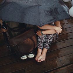 High angle view of couple sitting under umbrella on wet pier in rain