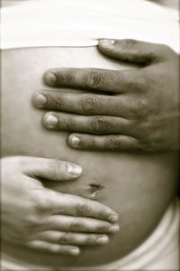 Midsection of pregnant woman with husband touching belly