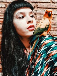 Close-up portrait of young woman with her parrot