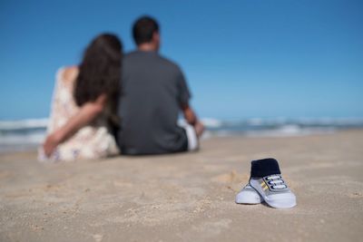 Rear view of couple sitting on beach