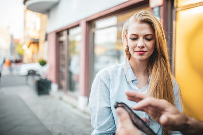 Young woman looking at man using smart phone in city