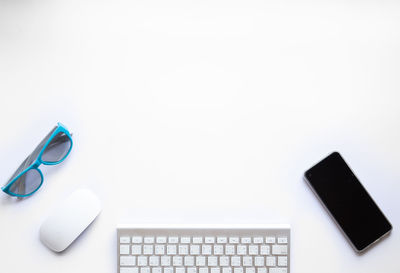 Directly above view of smart phone on table against white background