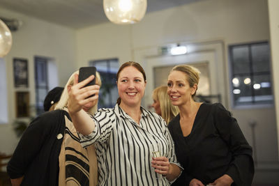 Women taking selfie at meeting in cafe