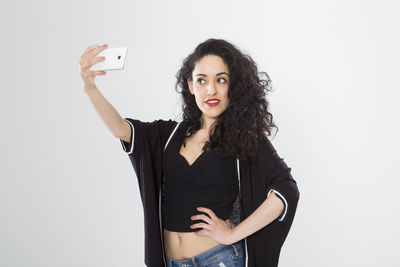 Portrait of beautiful young woman using mobile phone against white background