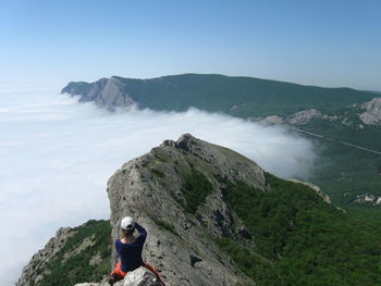 Rear view of woman sitting on mountain ridge