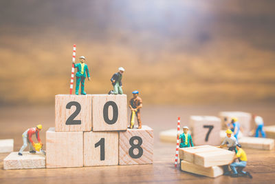 Figurines working over toy blocks with numbers on table