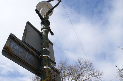 Low angle view of sign on pole against sky