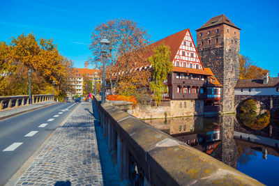 Canal amidst buildings against sky during autumn