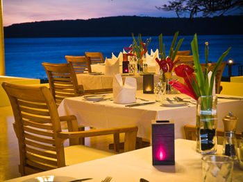 Chairs and tables at restaurant by sea against sky