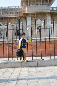 Cute boy looking away standing by railing in city