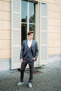 Portrait of young man standing against wall