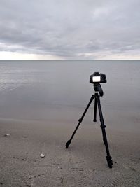 Close-up of camera on beach against sky