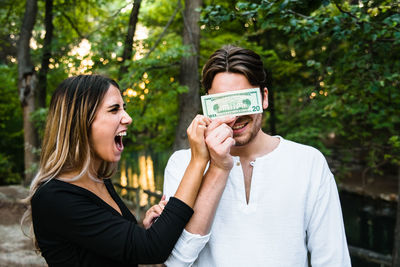 Woman holding paper currency against face of man