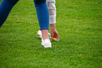 Low section of woman holding bottle on grassy field