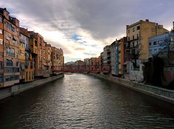 Canal in city against sky