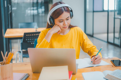 Portrait of young woman using laptop at office