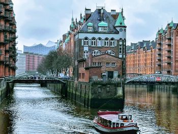 Bridge over river amidst buildings in city against sky